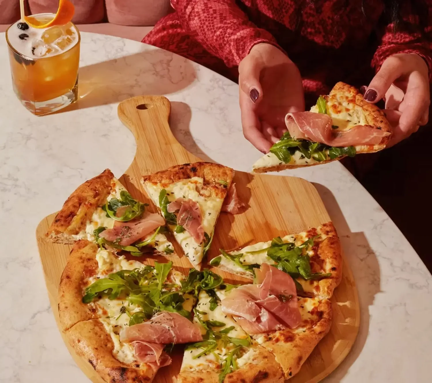 Freshly baked pizza and cocktails served at Twenty Sevens restaurant in Midtown Manhattan