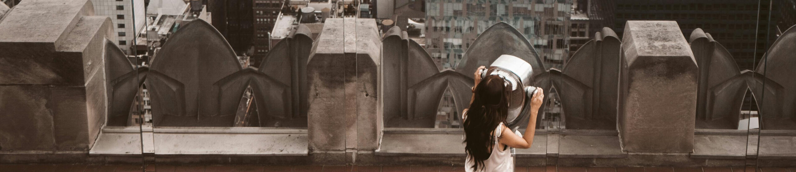 Guest looking through binoculars from a New York City rooftop